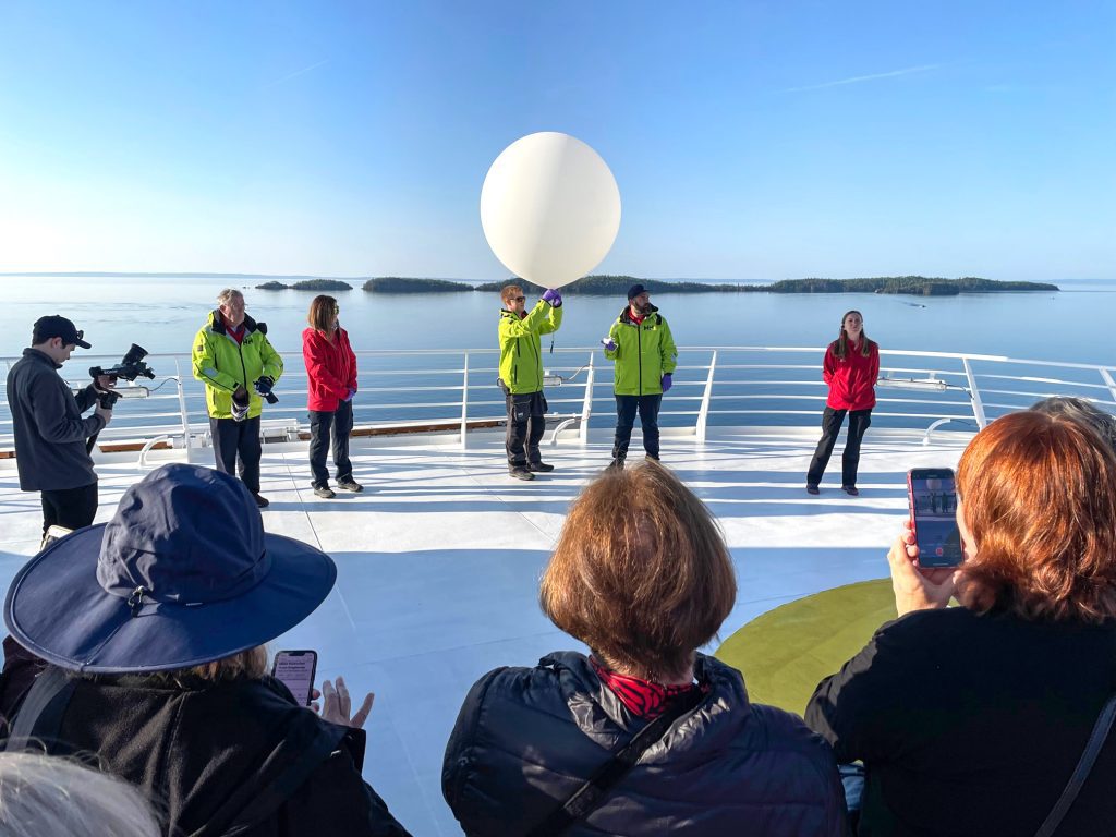 people watching scientists release a weather balloon aboard the Viking Octantis