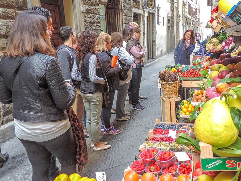 a group of people outside a vvegetable market