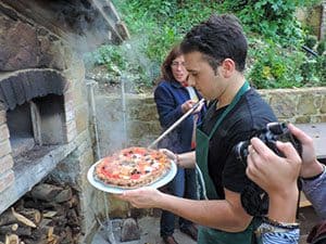 a man taking a pizza out of an oven  in a Florence cooking class