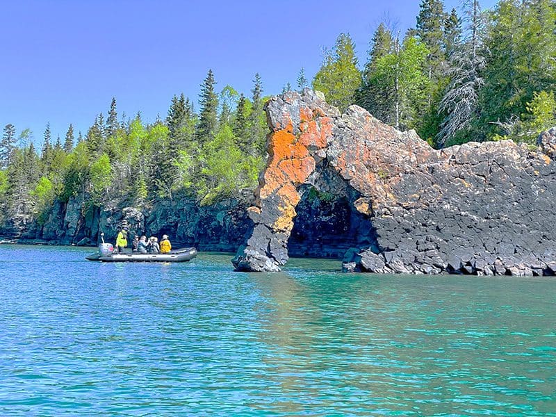 people on a zodiac looking at rock formations on a lake