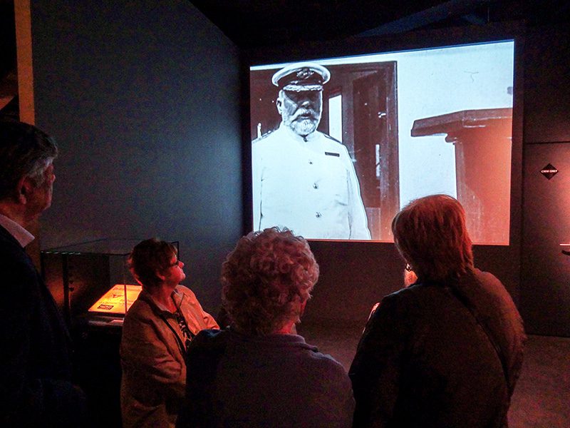 people looking at a photograph of a ship's captain