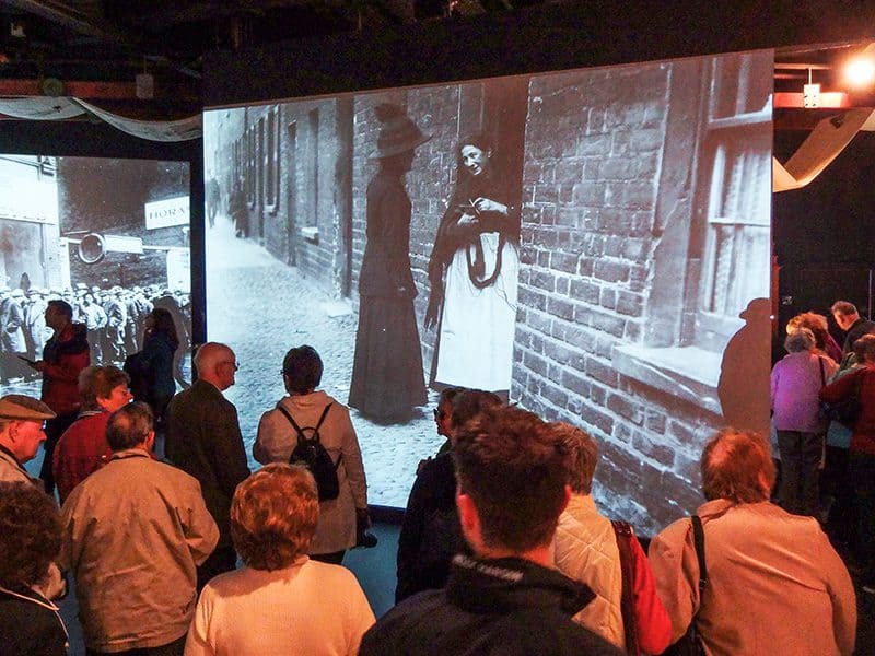 people looking at a large size photo of a street in old Belfast in the Titanic Museum Belfast