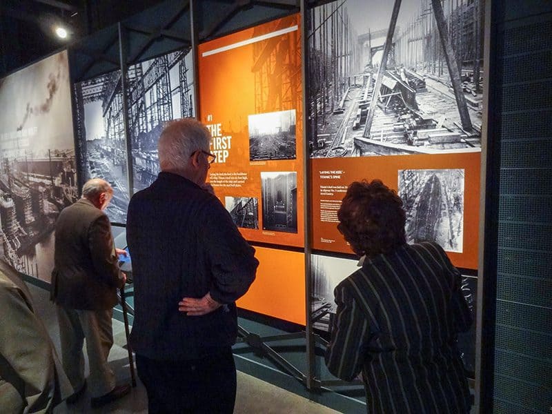 people looking at an exhibit of photos on a wall