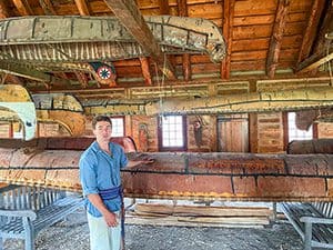 a young man standing in front of a display of birch-bark canoes