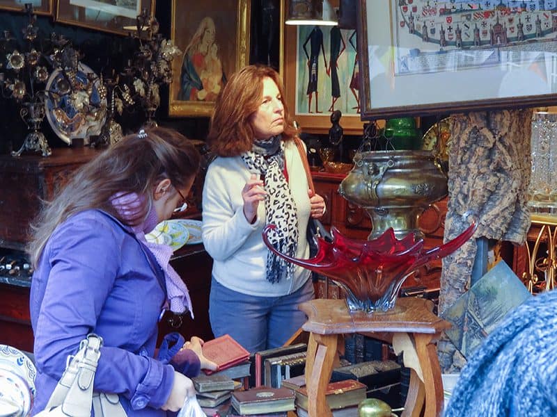 a woman looking at items in an antique market in one of the hidden gems in Europe