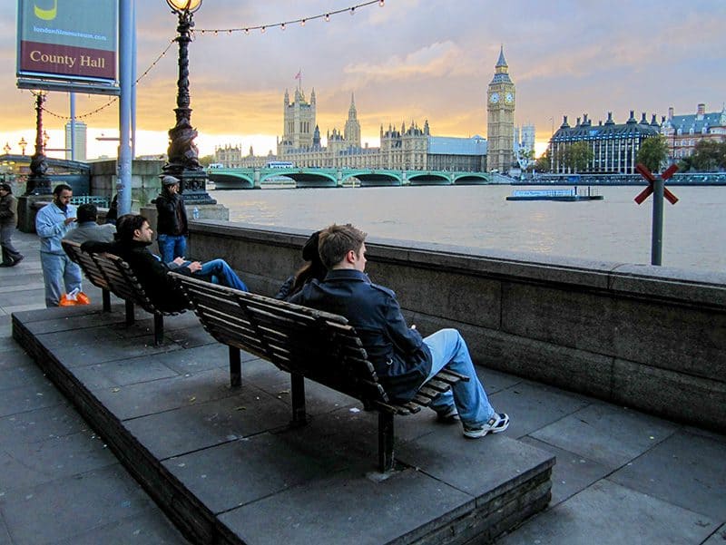 people on a bench on the Thames River at one of the hidden gems in Europe