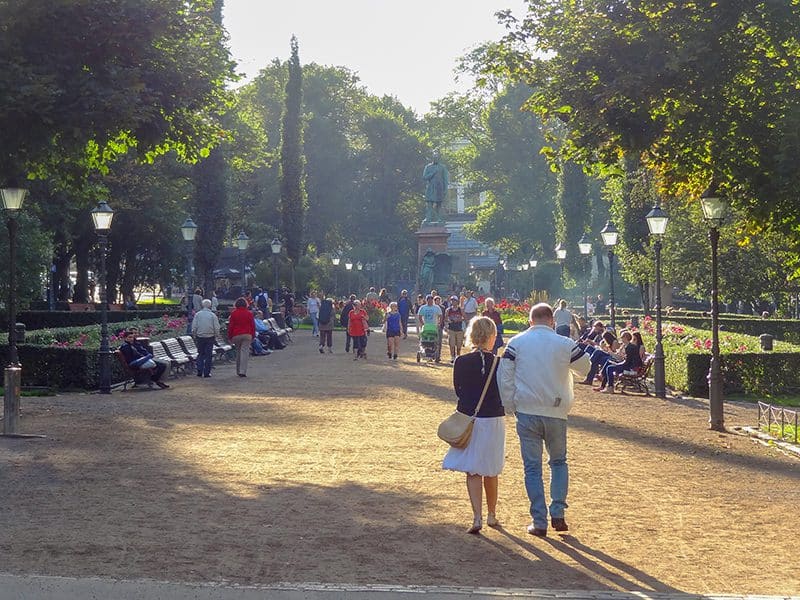 a crowd of people walking along a broad path in a park