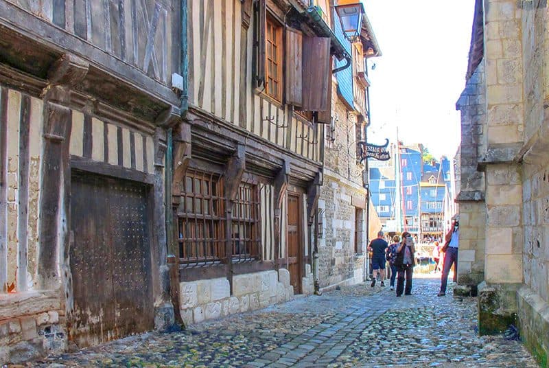 people walking down a narrow street with old buildings in Honfleur France