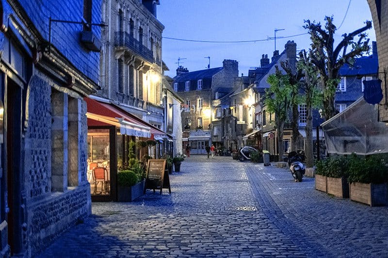 people walking along an old cobblestone street at dusk