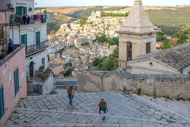 two women walking up a stairway with an old city in the distance