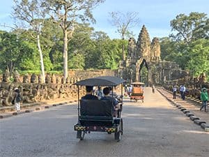 people riding in a tuk-tuk while visiting Angkor Wat