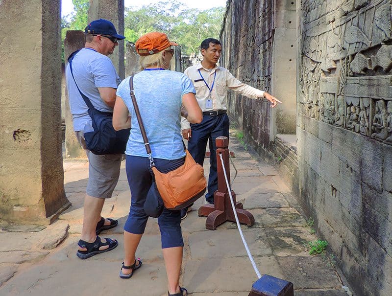 a guide and a couple viewing an ancient stone wall