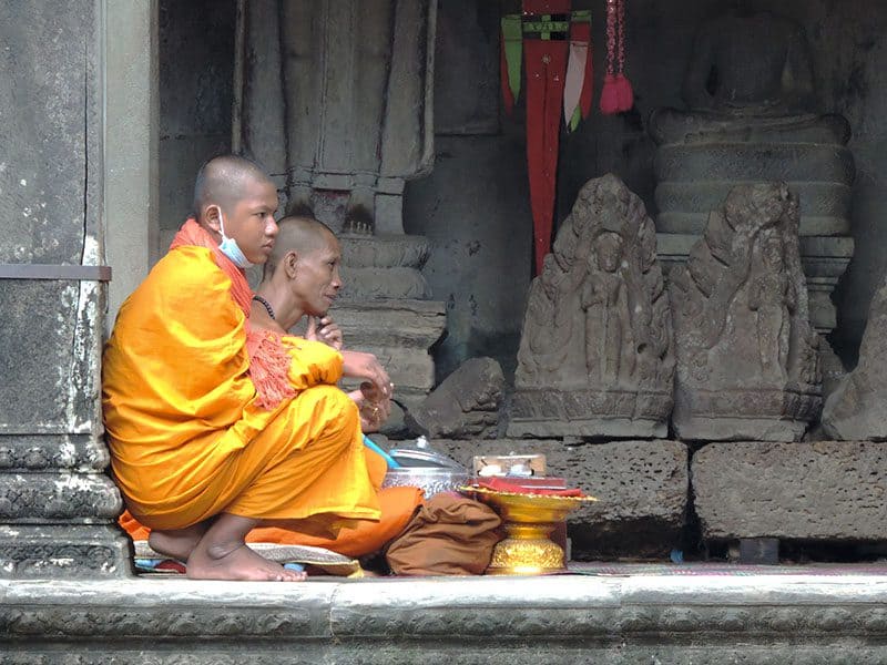 two monks sitting by ancient statues
