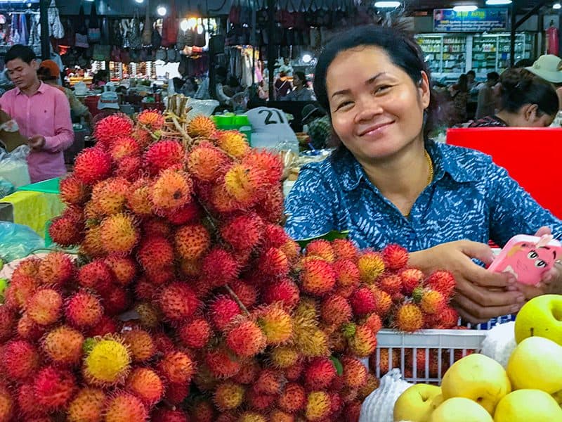 a smiling woman selling fruit