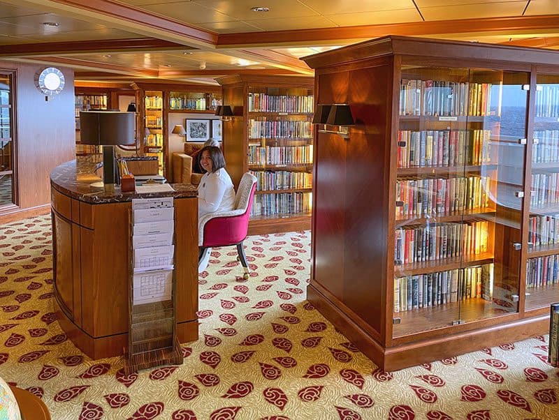 a oman sitting in the library on the Crystal Serenity