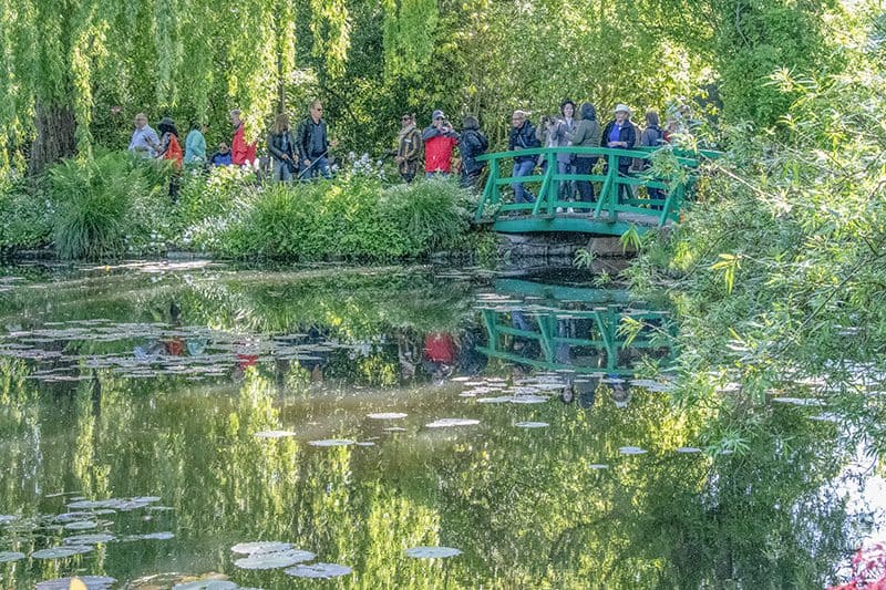 people on a green brifge looking at waterlilies in a pond on a Tauck river cruise