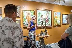 an artist with paintings on a wall talking with visitors