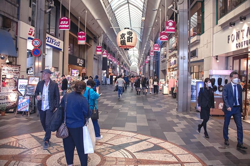 people walking though a covered mall with many shops