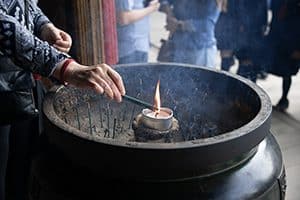 people lighting incense in a large stone bowl - one of the things to do in Kyoto when visiting a temple 