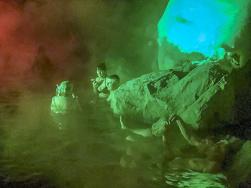 three people in a hot spring during winter in Alaska