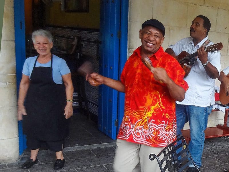 s street musician in a bright red shirt -- how to budget for a trip