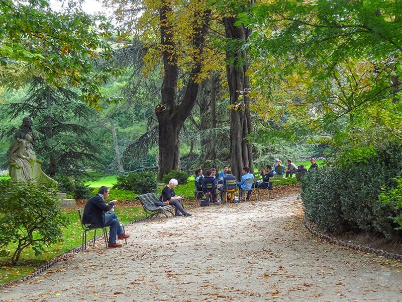people sitting along a path in a park