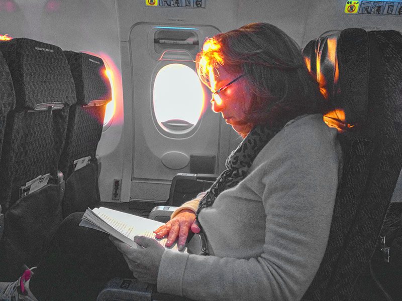 a woman sitting on a plane reading a book