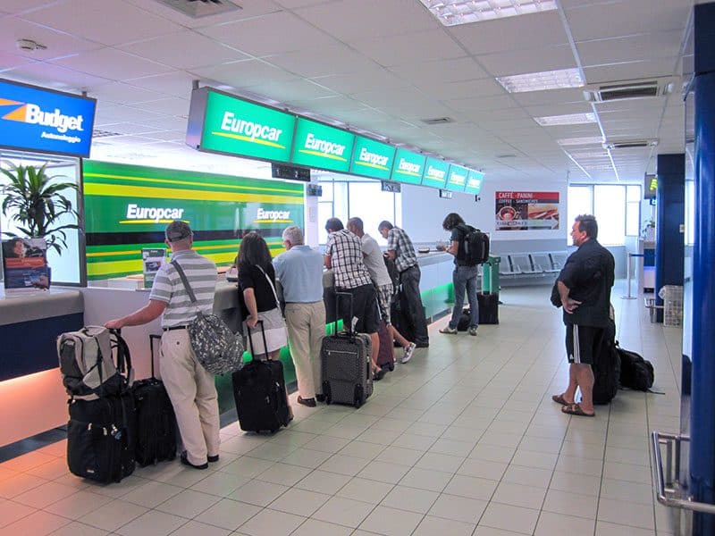 people waiting at a car rental desk -- how to budget for a trip