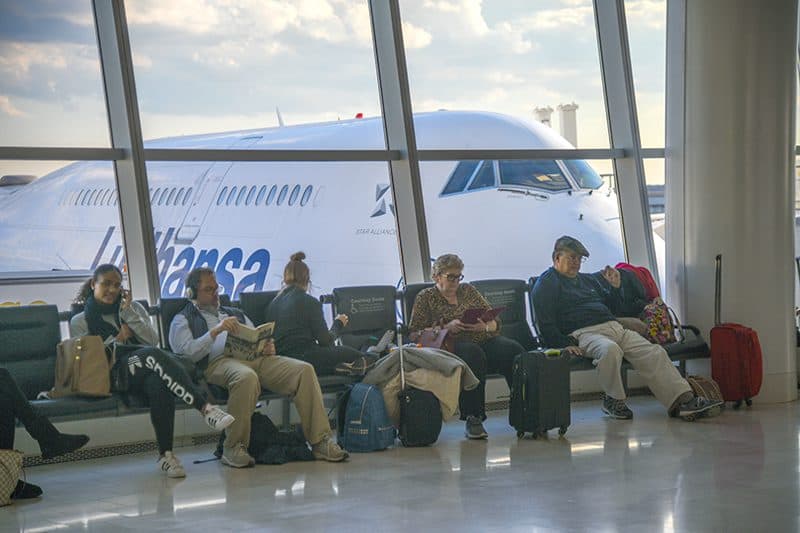 people in an airport lounge with a large plane behind them