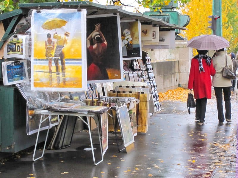 2 women walking past a art with old posters -- how to budget for a trip