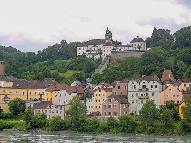 a church on a hillside above colorful houses near a river
