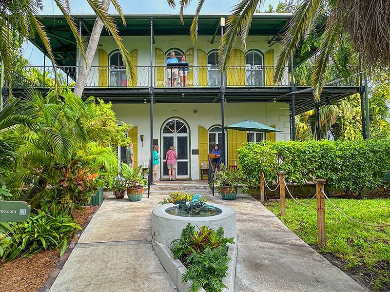 people outside a large house with large yellow shutters in the Florida Keys