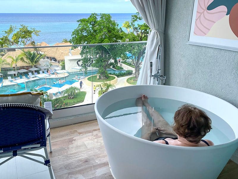 a woman in a hot tub on a balcony at looking at the Caribbean Sea