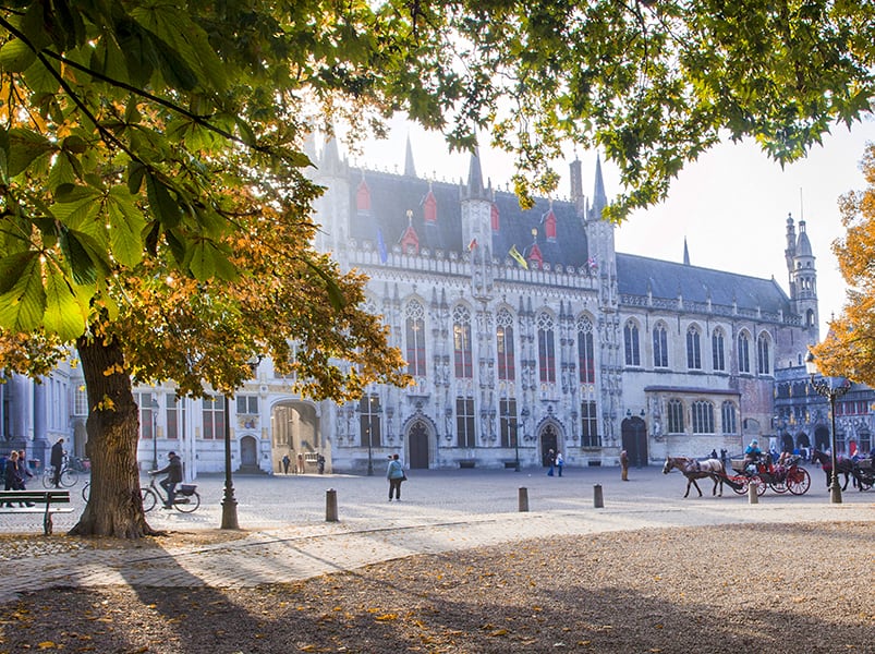 people in a square in front of a large gothic-style building