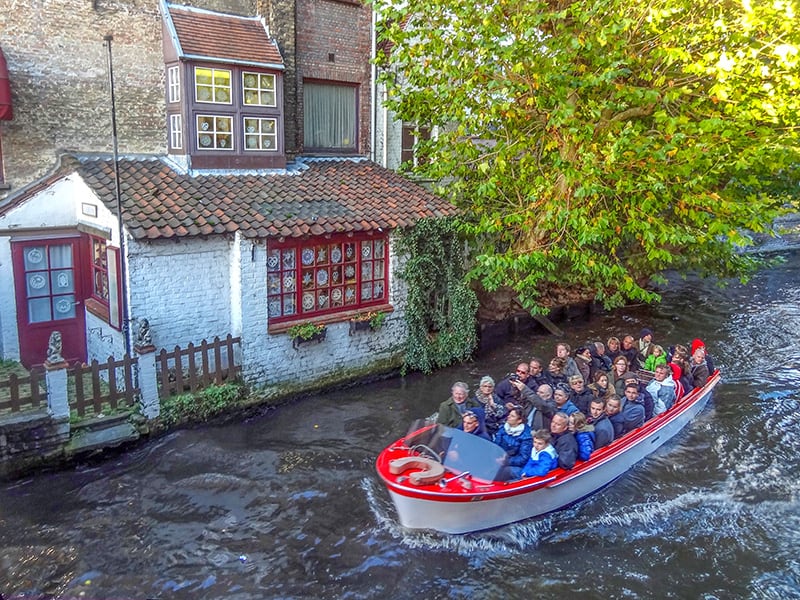 people in a canal boat passing a white building 