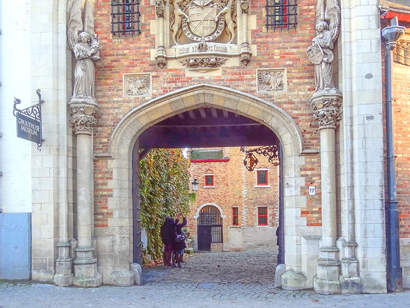 people entering the ornate entrance of an old building - things to do in Bruges