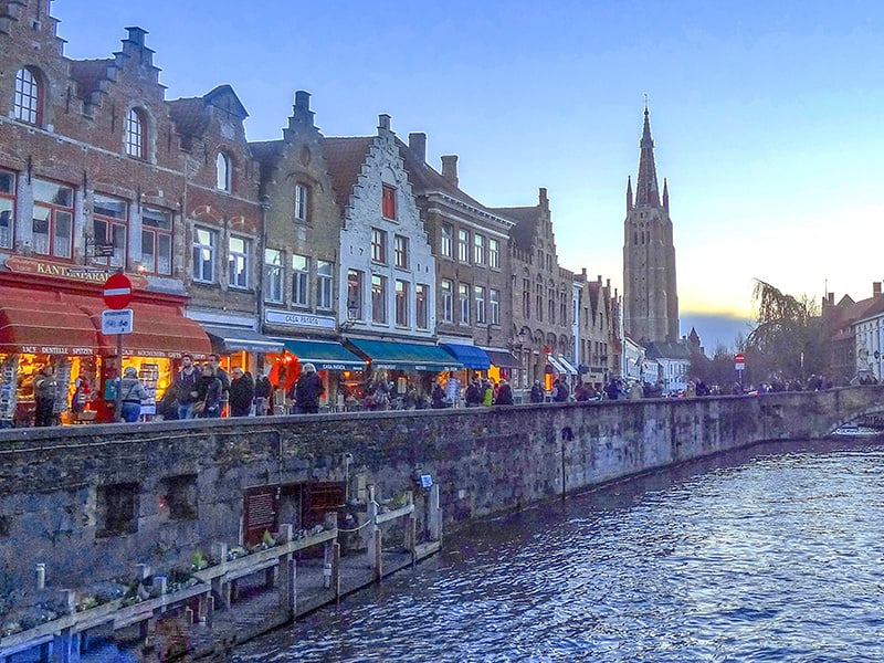 people walking along a city canal in the evening - one of things to do in Bruges