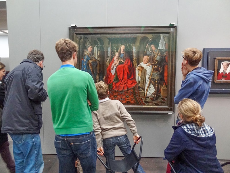a family in a museum looking at a painting  - one of things to do in Bruges