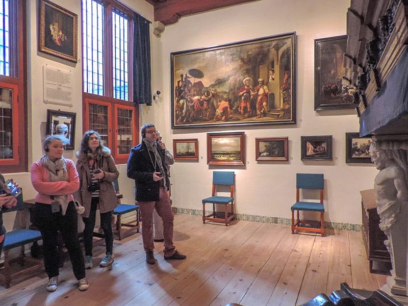 people looking at paintings on teh walls in Rembrandt's house seen during 2 days in Amsterdam