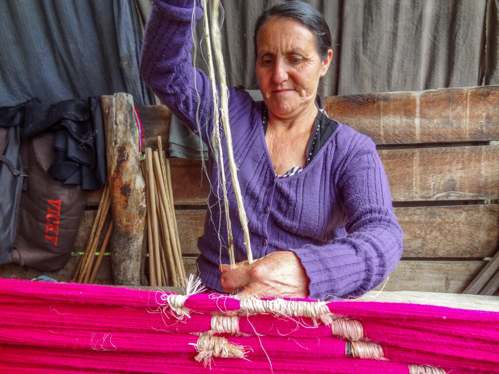 a woman in a purple sweater by a loom