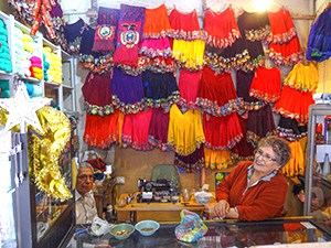 a woman surrounded by brightly colored clothing hanging from the ceiling