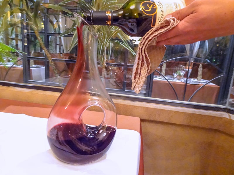 a bottle of wine being poured into a decanter 