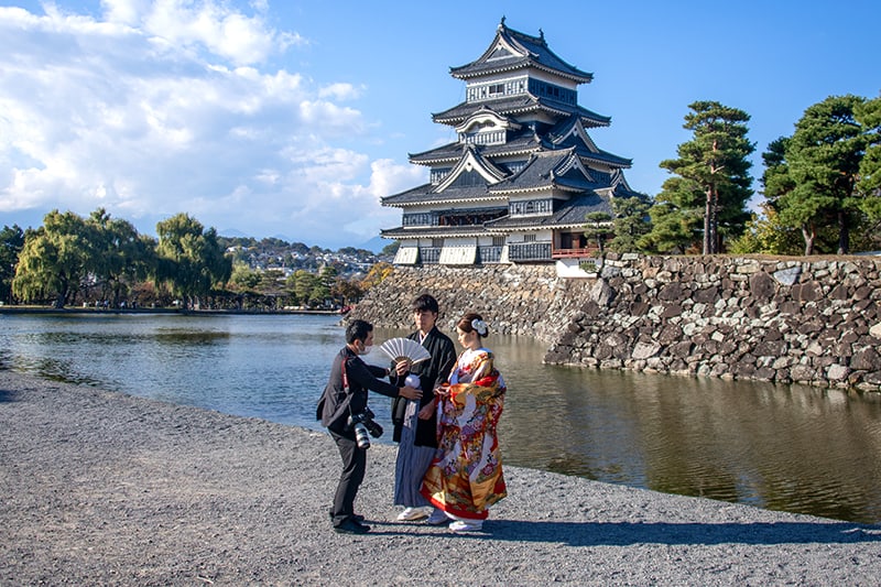 three people visiting the grounds of a huge ancient castle, one of the things to do in Japan