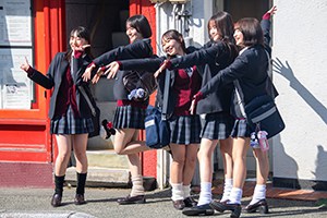 schoolgirls waving to pedestrians on a street