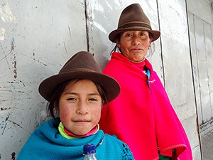 a mother and daughter with brown hats and colorful shawls
