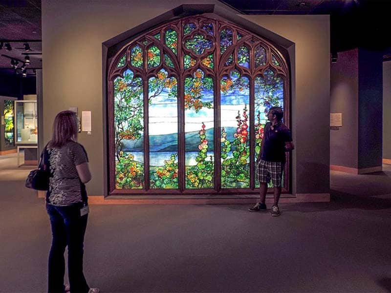 people looking at a a large stained glass window in the Glass Museum - one of the things to do in the finger lakes 