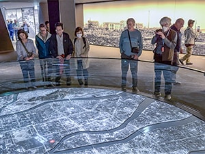 people in a museum looking at an exhibit of s destroyed city, one of the things to do in Japan