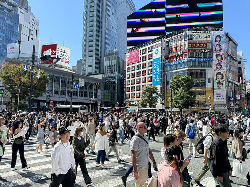 a huge crowd of people crossing a wide street intersection in Tokyo, one of the things to do in Japan