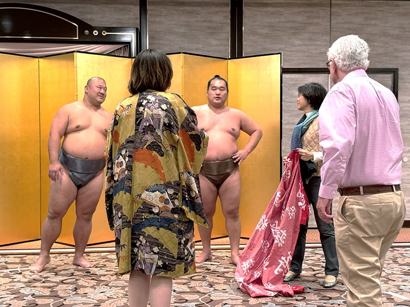 tourists speaking with two sumo wrestlers