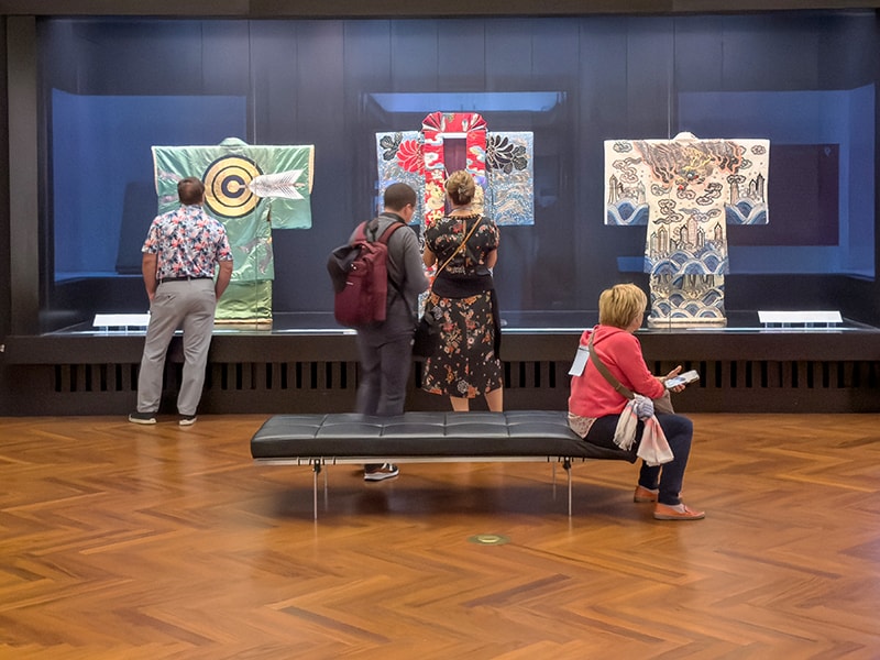 people looking at colorful kimono in a museum, one of the things to do in Japan
